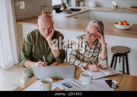 Gestresstes Seniorenpaar kalkulieren Ausgaben oder planen gemeinsam Haushalt zu Hause. Stockfoto