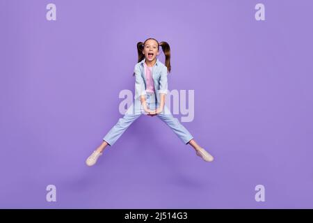 Foto von beeindruckt ziemlich kleinen Schulmädchen gekleidet Jeans Hemd springen hoch isoliert violette Farbe Hintergrund Stockfoto