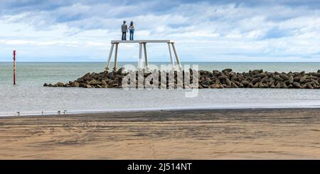 Auf einem Wellenbrecher vor dem Strand in Newbiggin Bay in Northumberland stehend, ist 'The Couple' eine 12,5 Meter hohe Skulptur des Künstlers Sean Henry. Stockfoto