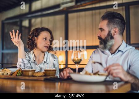 Ein erwachsenes Paar sitzt im Restaurant. Sie unterhalten sich beim Abendessen. Stockfoto