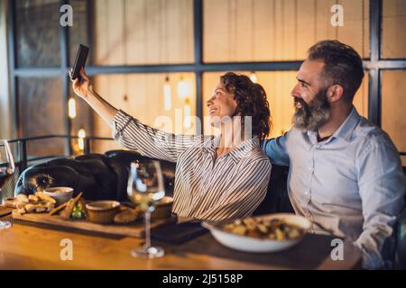 Glückliches Paar sitzt im Restaurant. Sie essen zu Abend mit Wein und verbringen eine schöne Zeit zusammen. Stockfoto