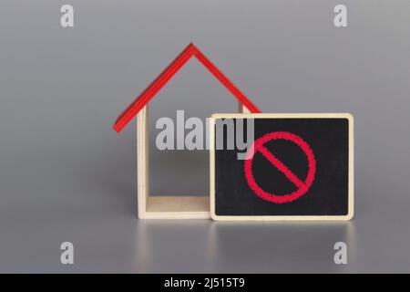Spielzeughaus und rotes Verbotsschild. Beschränkungen Bauverbot. Baubeschränkungen Stockfoto