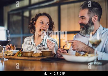 Ein erwachsenes Paar sitzt im Restaurant. Sie essen zu Abend mit Wein und verbringen eine schöne Zeit zusammen. Stockfoto