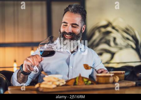 Ein glücklicher Erwachsener, der im Restaurant zu Abend gegessen hat und Wein getrunken hat. Stockfoto