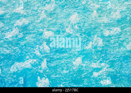 Blautürkisfarbenes Wasser in einem sprudelnden Pool mit Hydromassage, Texturhintergrund aus klarem Wasser. Stockfoto
