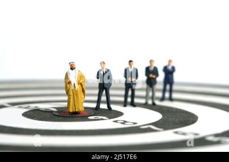 Miniatur Menschen Spielzeug Figur Fotografie. Teamarbeit im Unternehmen. Ein Sultan, der mit vier Geschäftsleuten in der Mitte der Dartscheibe steht. Isoliert auf weißem Rücken Stockfoto