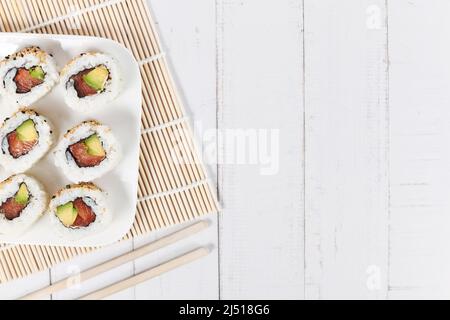 Sushi-Rollen mit Lachs, Avocado und Sesam auf dem Holztisch Stockfoto