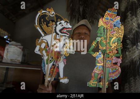 Ein Arbeiter, der in Sukawati, Gianyar, Bali, Indonesien, Lederpuppenfiguren des balinesischen Künstlers I Wayan Balik zeigt. Stockfoto