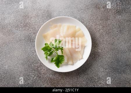 Köstliche geräucherte Heilbutt-Scheiben auf weißem Teller serviert, isoliert auf grauem Hintergrund. Blick von oben. Stockfoto