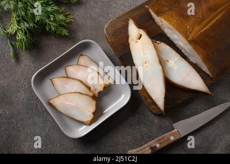 Frisch geräucherter Heilbutt auf braunem Hintergrund geschnitten. Blick von oben. Stockfoto