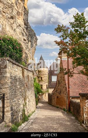 Die enge Fußgängerzone des mittelalterlichen Dorfes La Roque-Gageac erstreckt sich entlang steiler Klippen, eingebettet zwischen Steinmauern, die mit Efeu verschlungen sind. Dordogne Stockfoto