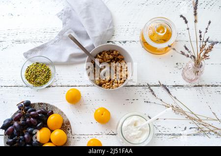 Frühstückskonzept mit Müsli, Honig, Joghurt und Obst Stockfoto