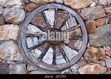 Holzrad im alten Stil in der Steinmauer Stockfoto