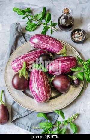 Auberginen auf dem Teller mit Kräutern, Olivenöl und Gewürzen Stockfoto