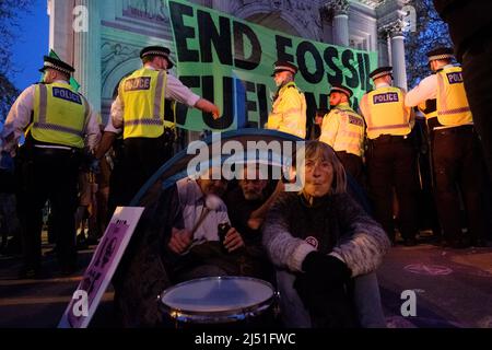 London, Großbritannien. 16. April 2022. Extinction Rebellion (XR)-Aktivisten sprangen auf eine Schwarze Limousine und saßen auf dem Boden und klebten sich in Marble Arch. Später wurde ein Transparent mit der Aufschrift ‘'Stop fossile Brennstoffe now' auf den Bogen gesetzt. Der heutige Tag war Teil einer einwöchigen Welle von Protesten und zivilen Ungehorsamsmaßnahmen, die die britische Regierung angesichts der Klimakrise und der ökologischen Notlage dazu aufforderte, die gesamte neue Infrastruktur für fossile Brennstoffe sofort zu stoppen. Stockfoto