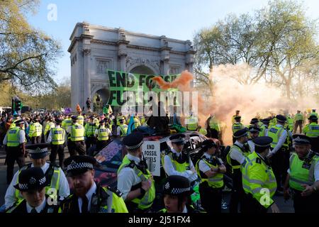 London, Großbritannien. 16. April 2022. Extinction Rebellion (XR)-Aktivisten sprangen auf eine Schwarze Limousine und saßen auf dem Boden und klebten sich in Marble Arch. Später wurde ein Transparent mit der Aufschrift ‘'Stop fossile Brennstoffe now' auf den Bogen gesetzt. Der heutige Tag war Teil einer einwöchigen Welle von Protesten und zivilen Ungehorsamsmaßnahmen, die die britische Regierung angesichts der Klimakrise und der ökologischen Notlage dazu aufforderte, die gesamte neue Infrastruktur für fossile Brennstoffe sofort zu stoppen. Stockfoto