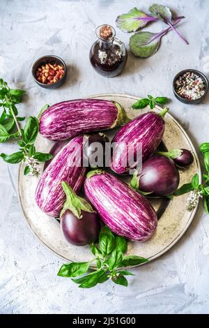 Auberginen auf dem Teller mit Kräutern, Olivenöl und Gewürzen Stockfoto