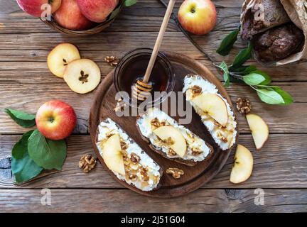 Brotscheiben mit Quark, Honig, Äpfeln und Nüssen im rustikalen Stil Stockfoto