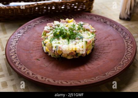 Salat mit Erbsen und Mayonnaise, serviert in einem Zylinder auf einem Tonteller Stockfoto