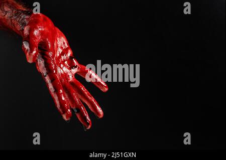 Nahaufnahme einer mit Blut befleckten männlichen Hand auf schwarzem Hintergrund. Stockfoto