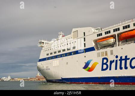 Brittany Ferries Autofähre 'Mont St. Michel', die in Portsmouth, Hampshire, England, im Hafen anlegt. Mit Flugzeugträger der Marine, der in der Ferne festgemacht wurde. Vie Stockfoto