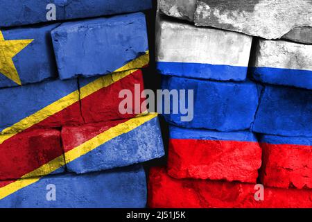 Konzept des Verhältnisses zwischen der Demokratischen Republik Kongo und Russland mit zwei bemalten Flaggen auf einer beschädigten Ziegelwand Stockfoto