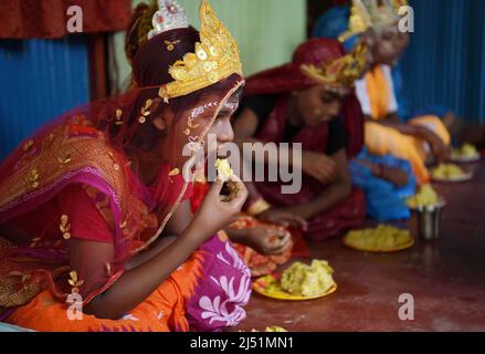 Folk-Künstler beim Mittagessen, bevor sie bei den Ritualen von Shiver Gajan, einem traditionellen hinduistischen Volksfest vor der Ernte am Stadtrand von Agartala, auftreten. Tripura, Indien. Stockfoto