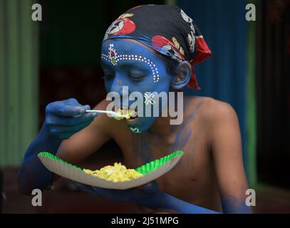 Folk-Künstler beim Mittagessen, bevor sie bei den Ritualen von Shiver Gajan, einem traditionellen hinduistischen Volksfest vor der Ernte am Stadtrand von Agartala, auftreten. Tripura, Indien. Stockfoto