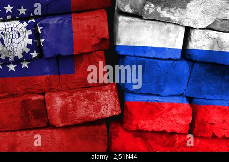 Konzept der Beziehung zwischen Myanmar, Burma und Russland mit zwei bemalten Fahnen auf einer beschädigten Ziegelwand Stockfoto