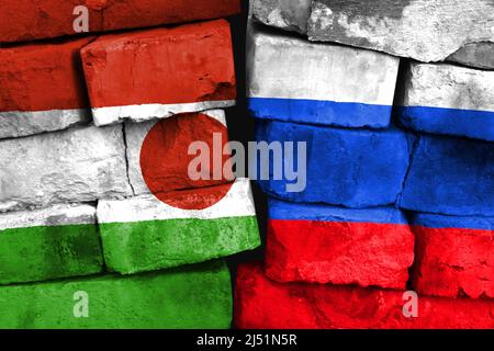 Konzept des Verhältnisses zwischen Niger und Russland mit zwei bemalten Fahnen auf einer beschädigten Ziegelwand Stockfoto