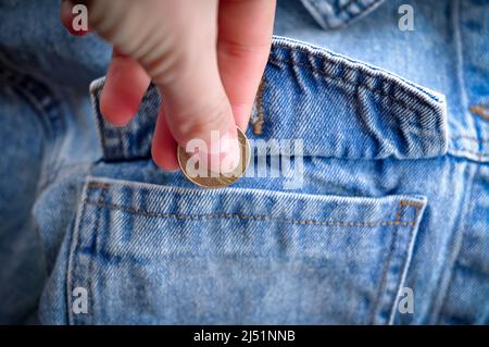 Hand legt Goldmünze Wechsel in Jeans Tasche Geld Konzept Stockfoto