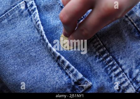 Hand legt Goldmünze Wechsel in Jeans Tasche Geld Konzept Stockfoto