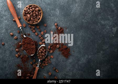 Hintergrund für Kaffeebohnen. Gerösteter Kaffee-Konzept mit verschiedenen Arten von Bohnen und Zimt-Sticks auf dunklem schwarzem Stein Hintergrund. Draufsicht. Kaffee CO Stockfoto