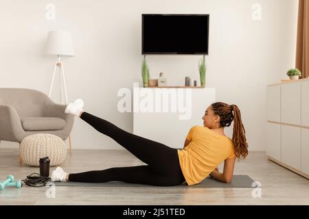Schwarzes Weibchen Macht Seitliches Bein Hebt Liegend Training Zu Hause An Stockfoto