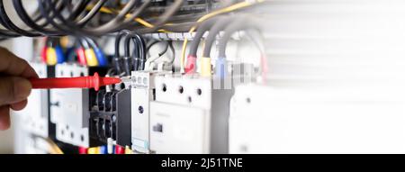 Ein Elektroingenieur überprüft die Funktion des Schaltschranks. Stockfoto