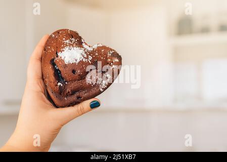 Mädchen hält in der Hand köstliche hausgemachte Schokoladenkekse mit zarten Rissen auf dem Hintergrund einer hellen Küche. Selbstkochkonzept. Frohe Weihnachten. Speicherplatz kopieren Stockfoto