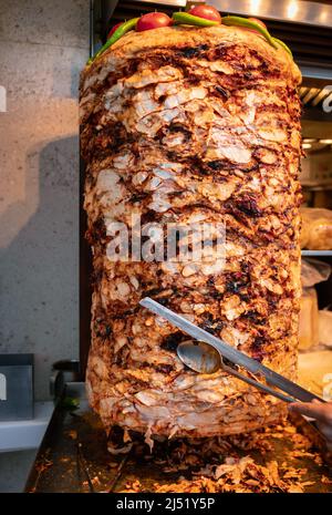 Küchenchef schneidet gegrilltes Lammfleisch aus rotierendem Spieß und macht in Istanbul traditionellen türkischen Straßenessendöner Kebab (Shawarma oder Gyros in anderen Kulturen) Stockfoto