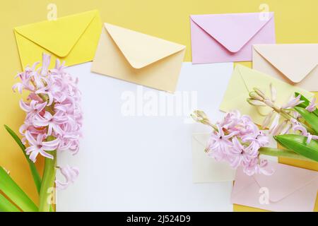 Bunte Umschläge und Hyazinthen-Blumen auf gelbem Hintergrund, Kopierraum. Stockfoto