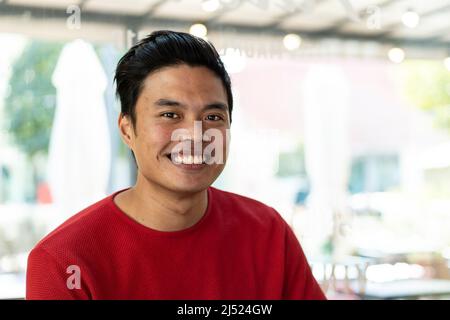 Junger asiatischer Mann lächelt in der Kamera - Fokus auf Gesicht Stockfoto