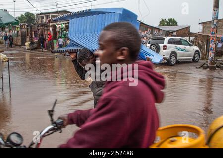 Ein Mann, der einen Plastikstuhl auf seiner Schulter trägt, durchquert am 18. April 2022 in Kibera einen von starken Regenfällen überfluteten Bereich. Die Regenzeit erweckt die drouhgt betroffenen Gebiete zum Leben, aber für die Bewohner von Kibera können die Regenfälle ein Zeichen für das Schlimmste sein, das kommen wird ( Foto von Samson Otieno/Sipa USA) Stockfoto