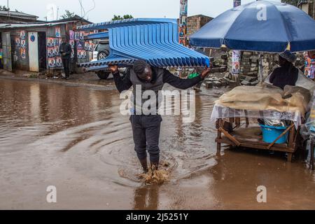 Ein Mann, der einen Plastikstuhl auf seiner Schulter trägt, durchquert am 18. April 2022 in Kibera einen von starken Regenfällen überfluteten Bereich. Die Regenzeit erweckt die drouhgt betroffenen Gebiete zum Leben, aber für die Bewohner von Kibera können die Regenfälle ein Zeichen für das Schlimmste sein, das kommen wird ( Foto von Samson Otieno/Sipa USA) Stockfoto