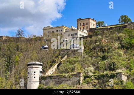 Koblenz, Deutschland - April 2022: Seilbahnen bringen Besucher zur Festung Ehrenbreitstein, die auf einem Hügel über dem Rhein thront. Stockfoto