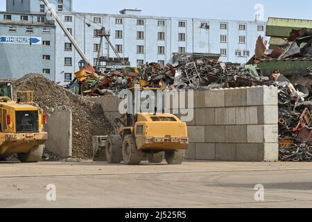 Basel, Schweiz - April 2022: Ein mechanischer Bagger arbeitet auf einer Altmetall-Recycling-Werft im Hafengebiet der Stadt. Stockfoto