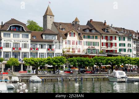 Rapperswil, Schweiz - 10. Mai 2016: Gebäude, Hotels und festfahrende Boote entlang der Promenade am See, all das zeigt die Vielfalt der Touristen an Stockfoto