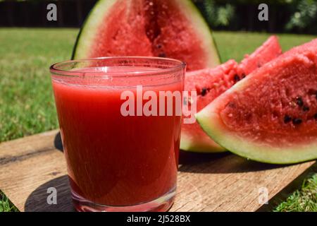 Wassermelone Saft Getränk mit frisch geschnittenem Wasser Melone Obst serviert im Freien Umgebung Hintergrund. Frische und leckere rote Farbe Tarbooz ka Sharbat Stockfoto