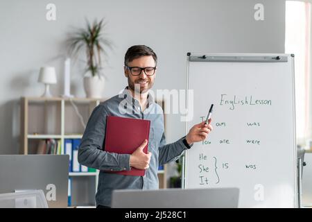 Englisch lernen online. Fröhlich reifen männlichen Lehrer geben Online-Fremdsprachenunterricht, mit Computer im Büro Stockfoto