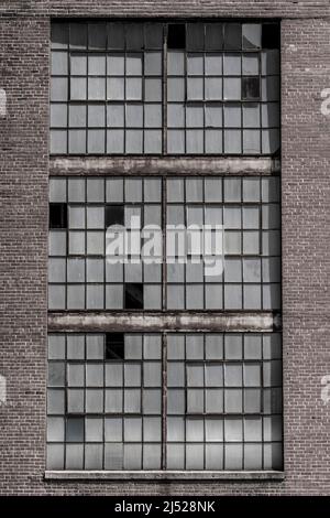 Kaputte Fenster und abgenutzte Außenflächen eines verlassenen Kohlekraftwerks. Kohlekraftwerke werden zugunsten erneuerbarer Energiequellen eingestellt. Stockfoto