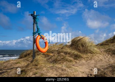 Eine gebrettete Life Boje, die in der Meeresbrise in den Sanddünen der Embleton Bay, Northumberland Coast, England, weht Stockfoto