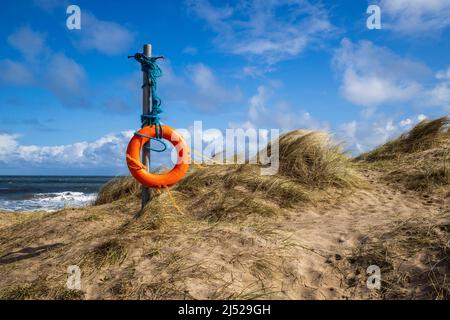 Eine gebrettete Life Boje, die in der Meeresbrise in den Sanddünen der Embleton Bay, Northumberland Coast, England, weht Stockfoto