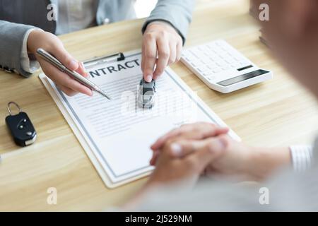 Versicherungskonzept der Autovermittler unterstützt seinen Kunden und erklärt die Details des Autokontakts. Stockfoto